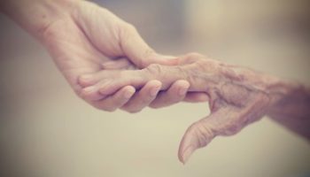 Grandparent hand holding teenager hand close-up warm light